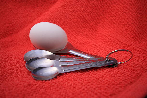 measuring spoons with egg on red stock photo