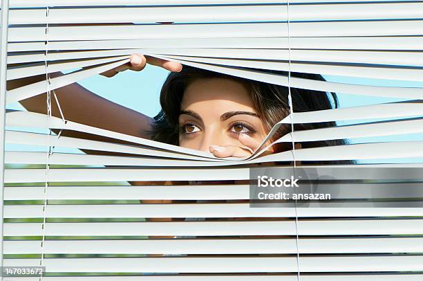 Niña Mirando A Través De Las Persianas Foto de stock y más banco de imágenes de Adulto - Adulto, Curiosidad, Dedo humano