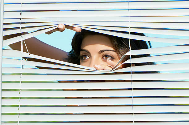 istock girl looking through the blinds 147033672