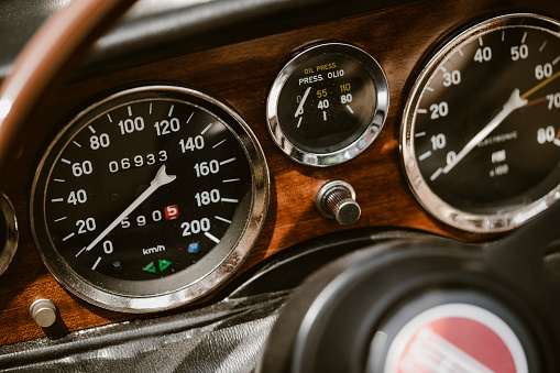 Close up shot of a speedometer and other gauges on an old vintage car.