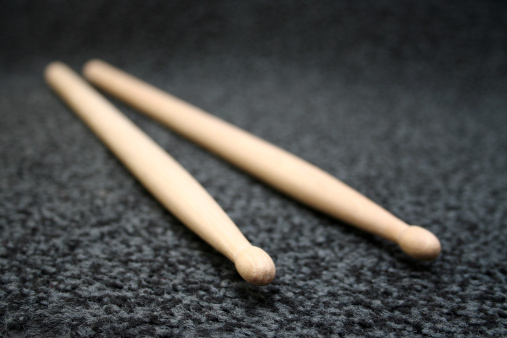 low angle, macro shot of the tips of wooden drumsticks on grey carpet