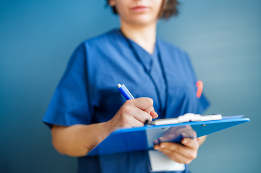 Healthcare Worker with medical records attached to a blue clipboard