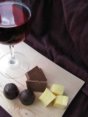Still life.  Wineglass of wine and slices of cheese and chocolate