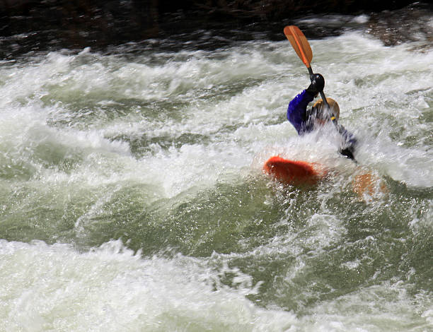 Orange kayak in middle of rapids stock photo