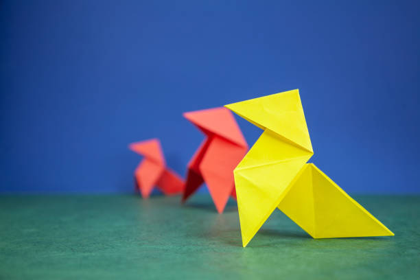 Paper hen origami over green and blue background stock photo