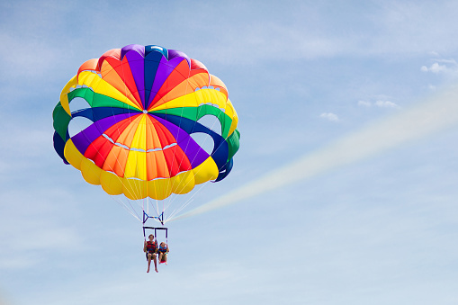 Kids parasailing. Water sport on summer vacation. Brother and sister flying in tropical ocean resort. Sea and beach fun. Rainbow parachute. Teenage boy and little girl fly.