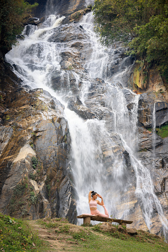 Health Asia woman travel and do yoga exercise at front view of waterfall