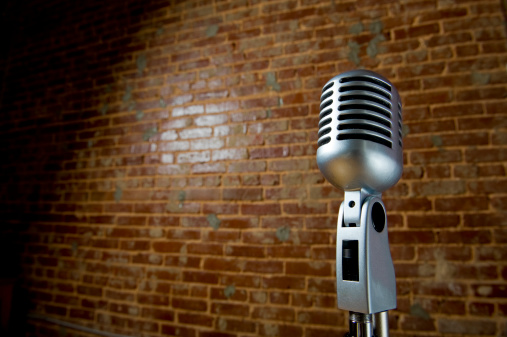 A vintage looking microphone in front of an old brick wall with copy space