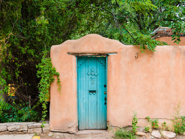 Rustic turquoise door set in an old adobe wall in Santa Fe, New Mexico