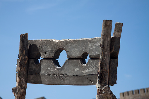 Wooden medieval pillory against a deep blue sky. This medieval punishment