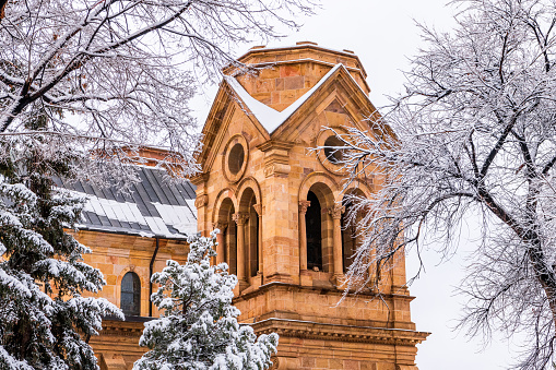 Snowy winter scene of church bell tower and snow-covered trees in Santa Fe, New Mexico