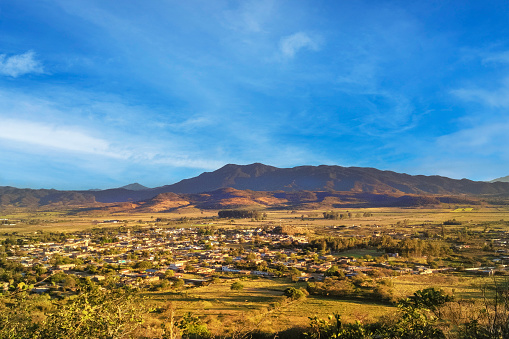 The lush valley spreads out with the small rural village of San Marcos in Jalisco Mexico. There are distant barren mountains in the background. It is a beautiful blue sky day. Copy Space at the top of the image.