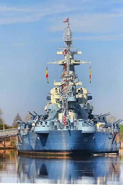 The World War II battleship USS North Carolina, across the Cape Fear River in Wilmington, NC with intense color and deep reflection in water