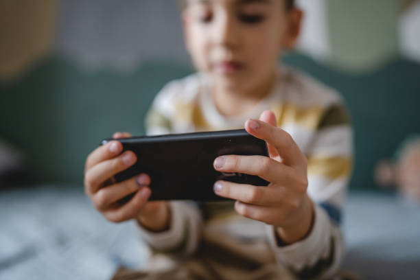 One caucasian boy child use smartphone mobile phone at home play games stock photo