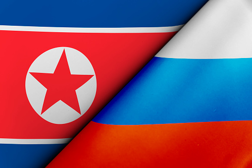 waving colorful flag of russia and national flag of north korea. The concept of international relations between countries. Sanctions against Russia. The state of governments. Friendship of peoples.