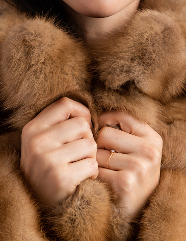 Woman holding her fur with her hands. Close-up. His face is not visible. The texture of the fur is visible. Unbranded fur.