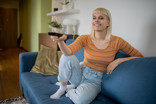 Young woman watching TV at home and enjoying
