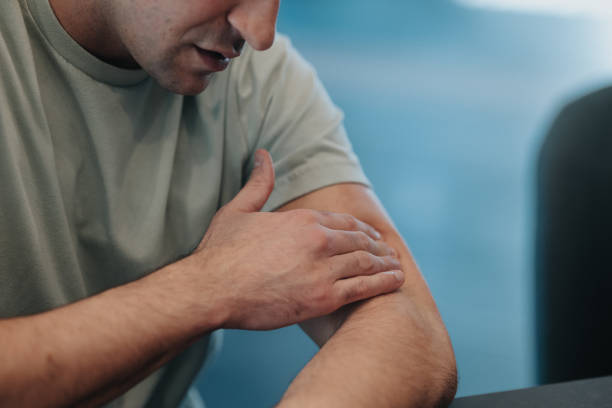 Unrecognizable man applying cannabis topical ointment for pain relief Cropped image of an unrecognizable man at home applying CBD topical ointment for pain relief to sore muscles on his arm. rubbing arm stock pictures, royalty-free photos & images