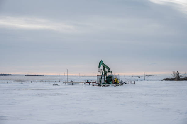 Oil pump jack in winter Oil pump in winter in the oil fields of Alberta, Canada. oil pump oil industry alberta equipment stock pictures, royalty-free photos & images