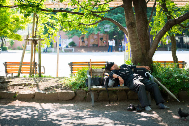 Homeless man sleeping on park bench in Tokyo