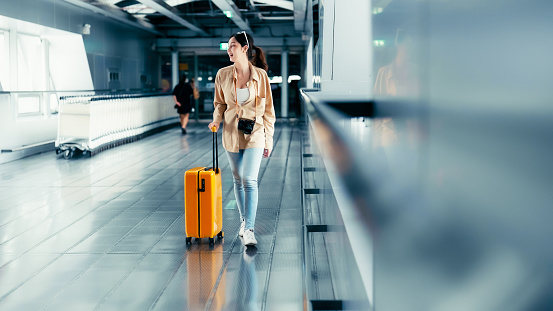 International airport terminal. Asian beautiful woman with luggage and walking in airport