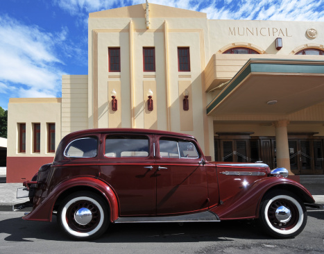 An old car parked outside a cinema that was built in Art Deco style following a major earthquake in 1931. Napier, New Zealand.