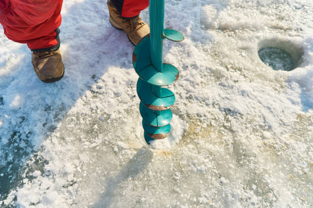 istock A warmly dressed Asian guy drills a hole in the ice on winter fi 1470389317