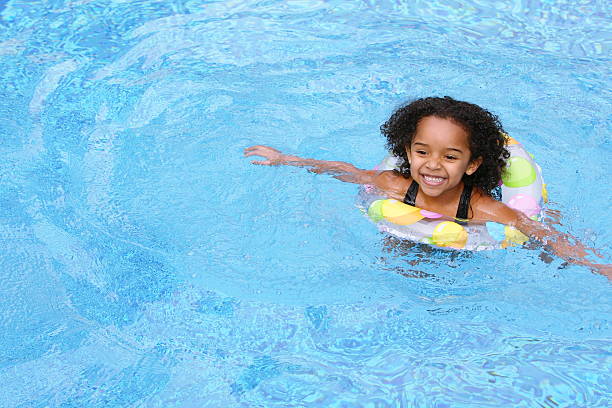 istock Young girl in swimming pool with colored floating ring 147039596