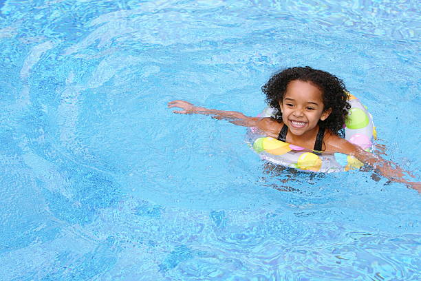 Young girl in swimming pool with colored floating ring stock photo