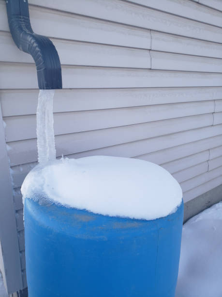 istock Frozen water flowing from a downspout onto a blue rainwater tank. 1470398767