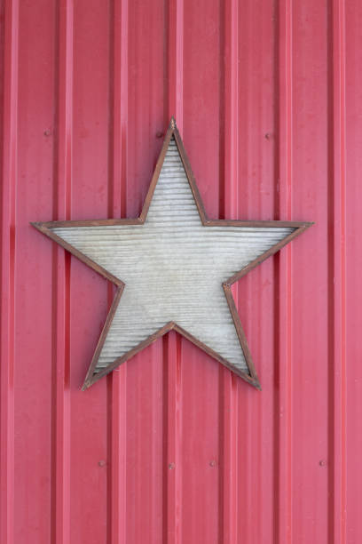 istock Five pointed tin star outlined in wood, hanging on a red metal wall 1470398772