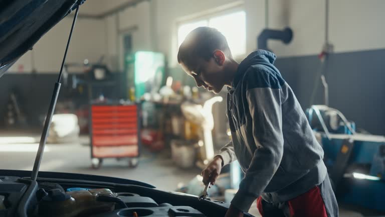 SLO MO A young car mechanic repairs a car engine