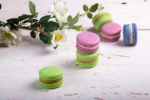 A variety of delicate almond French macaroon biscuits on a light wooden table close-up