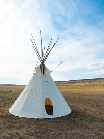 A teepee on the prairie. Horizontal image. Colour. First Nations culture. Teepee is also tipi. Aboriginal culture and historic attractions are popular on the great plains, which has a rich history of many tribes and peoples who were here long before white people settled these vast areas. This tipi is located in southern Alberta near the Head-Smashed-In Buffalo Jump, a major tourist attraction and museum in Alberta, Canada. 