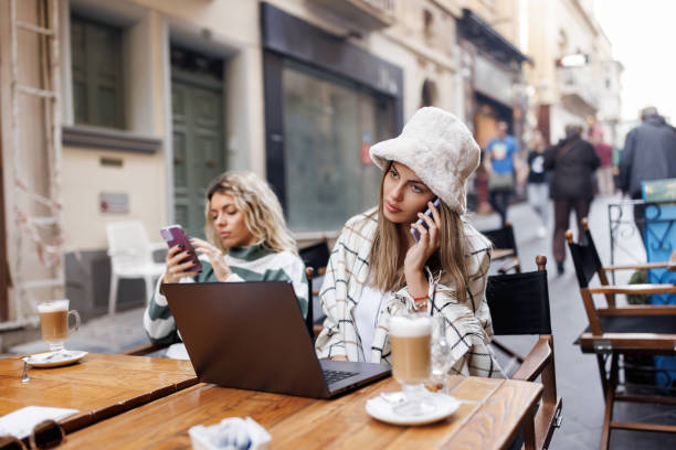 istock Female friends using technology in sidewalk cafe 1470409175