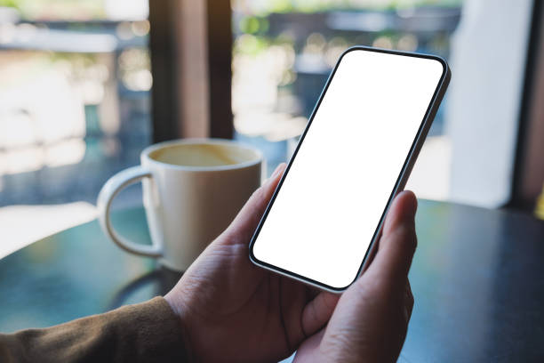 istock Mockup image of hands holding mobile phone with blank desktop screen with coffee cup on the table 1470409259