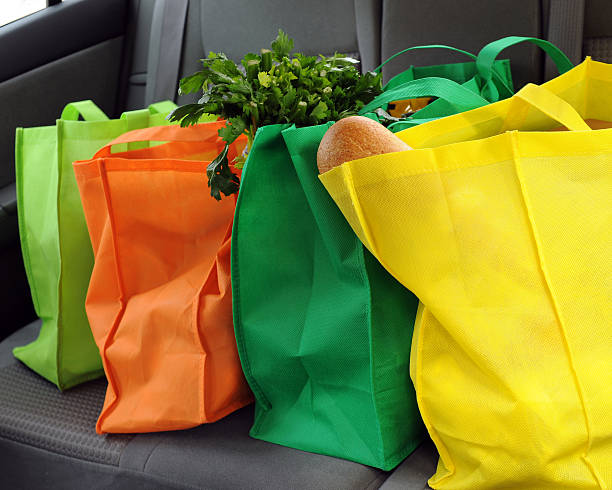 Shopping Green Four filled and colorful eco-friendly shopping bags in the back seat of a car. reusable bag stock pictures, royalty-free photos & images