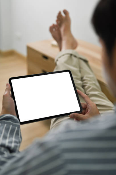 istock Over shoulder man in casual cloth putting legs on table and using digital tablet. 1470417806