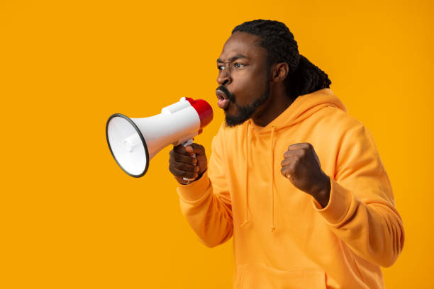 istock Young african man against yellow background with megaphone 1470423857