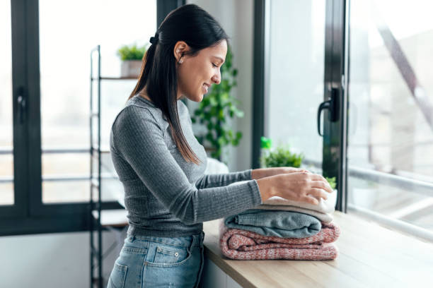 istock Young woman folding clothes on a table at home 1470427465
