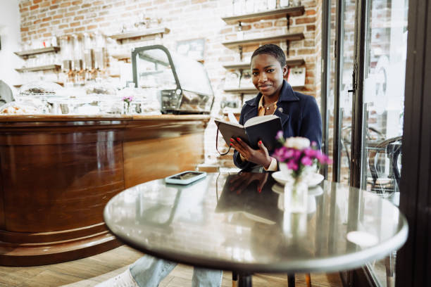 istock Beautiful african girl making notes in diary in cafeteria. 1470427631
