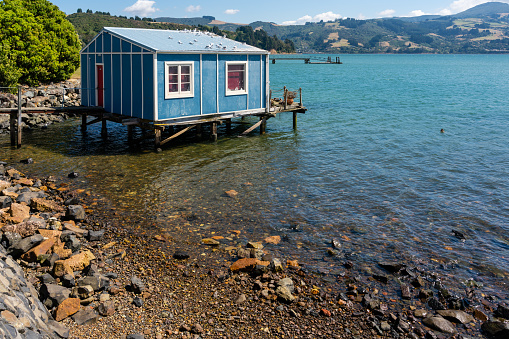 Uitzicht over de baai Broad Bay met een boothuis op palen aan de baai van Broad Bay bij Dunedin, Nieuw-Zeeland