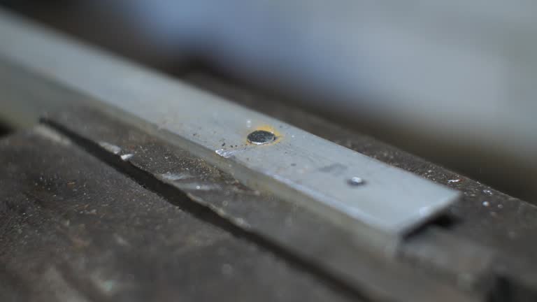 In the workshop of a man, he hammers a metal rivet with a hammer. The master fastens the metal with a rivet and a hammer. The rivet is hammered into the metal sheet with a hammer.