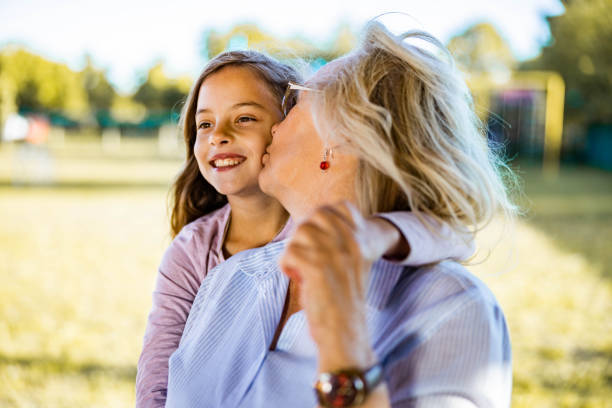 Senior woman kissing her small granddaughter in nature.
