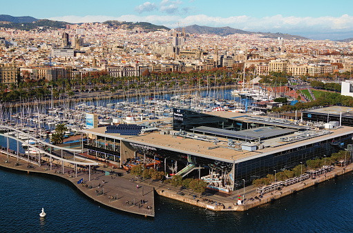 Barcelona, Spain-January 02,2016:Aerial view of Maremagnum shopping mall in harbor. Scenic landscape view embankment with moored yachts and boats. Ancient buildings in the background.
