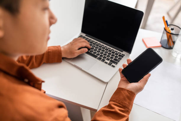 istock Asian Businessman Using Smartphone And Laptop With Empty Screens Indoor 1470439989