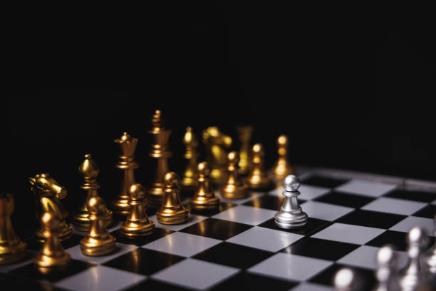 istock Silver pawn chess move forward to facing and challenge all gold chess pieces on the chessboard on black background. Leadership mindset and teamwork concept. 1470440522