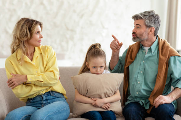 istock Unhappy Daughter Sitting Between Parents While They Having Quarrel Indoors 1470440690
