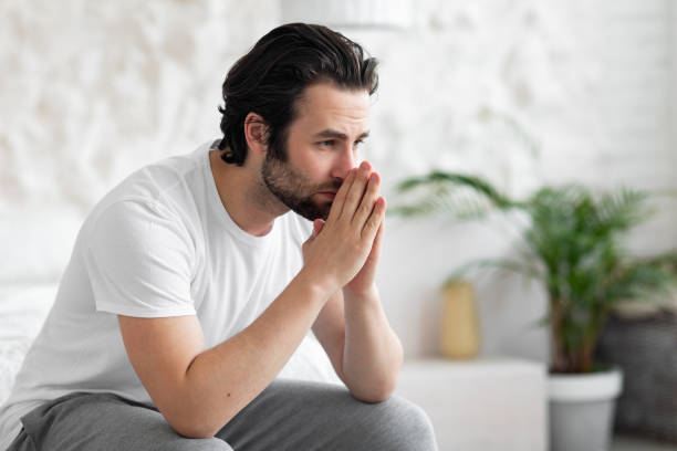 istock Unhappy young man sitting on bed alone, copy space 1470440803