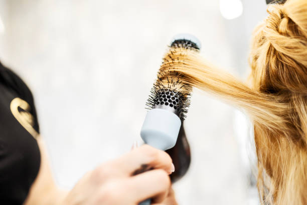 Hairdresser using hairdryer tool to dry clients lock of hair